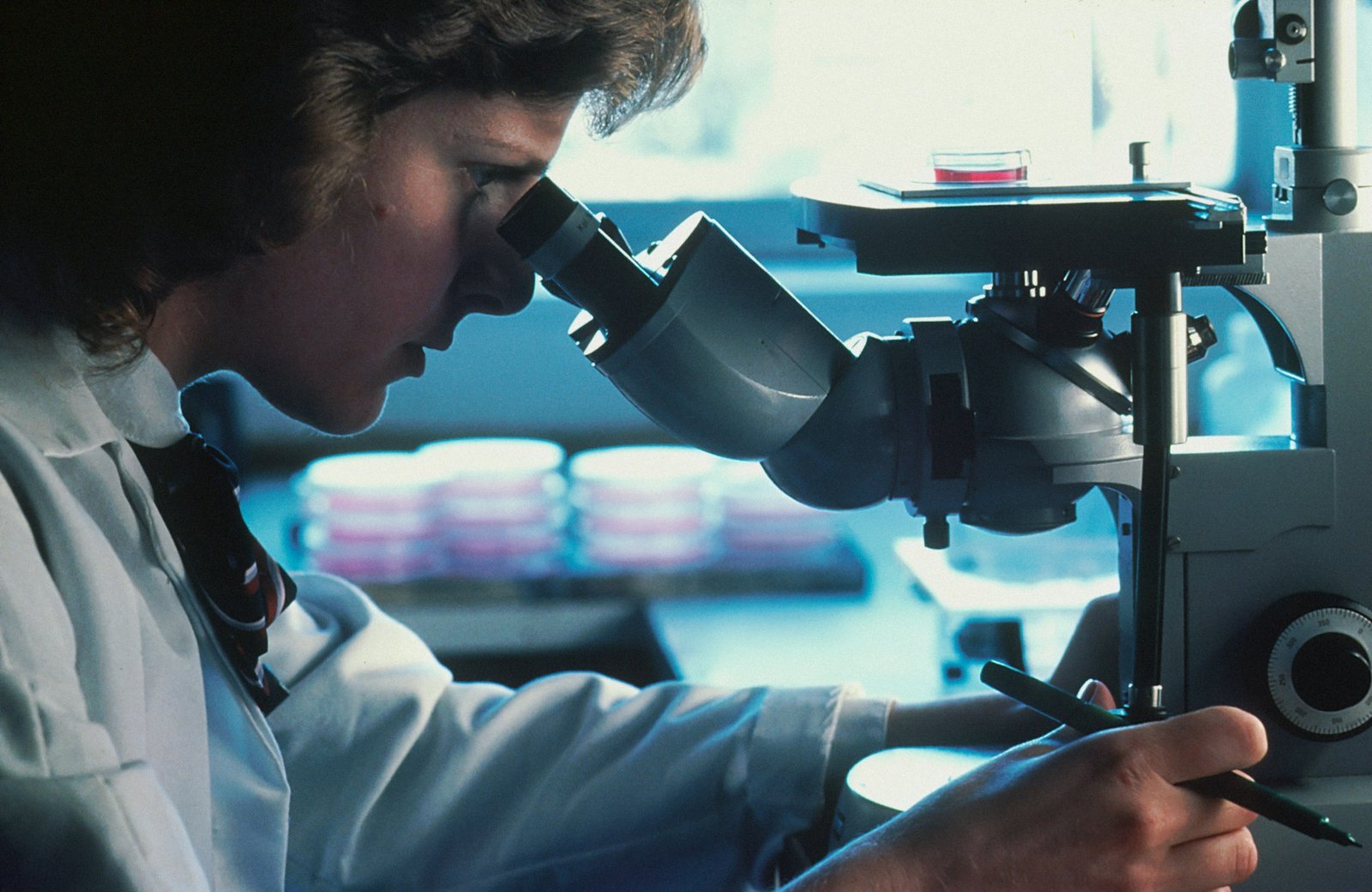 Scientist in a lab coat looking through a microscope